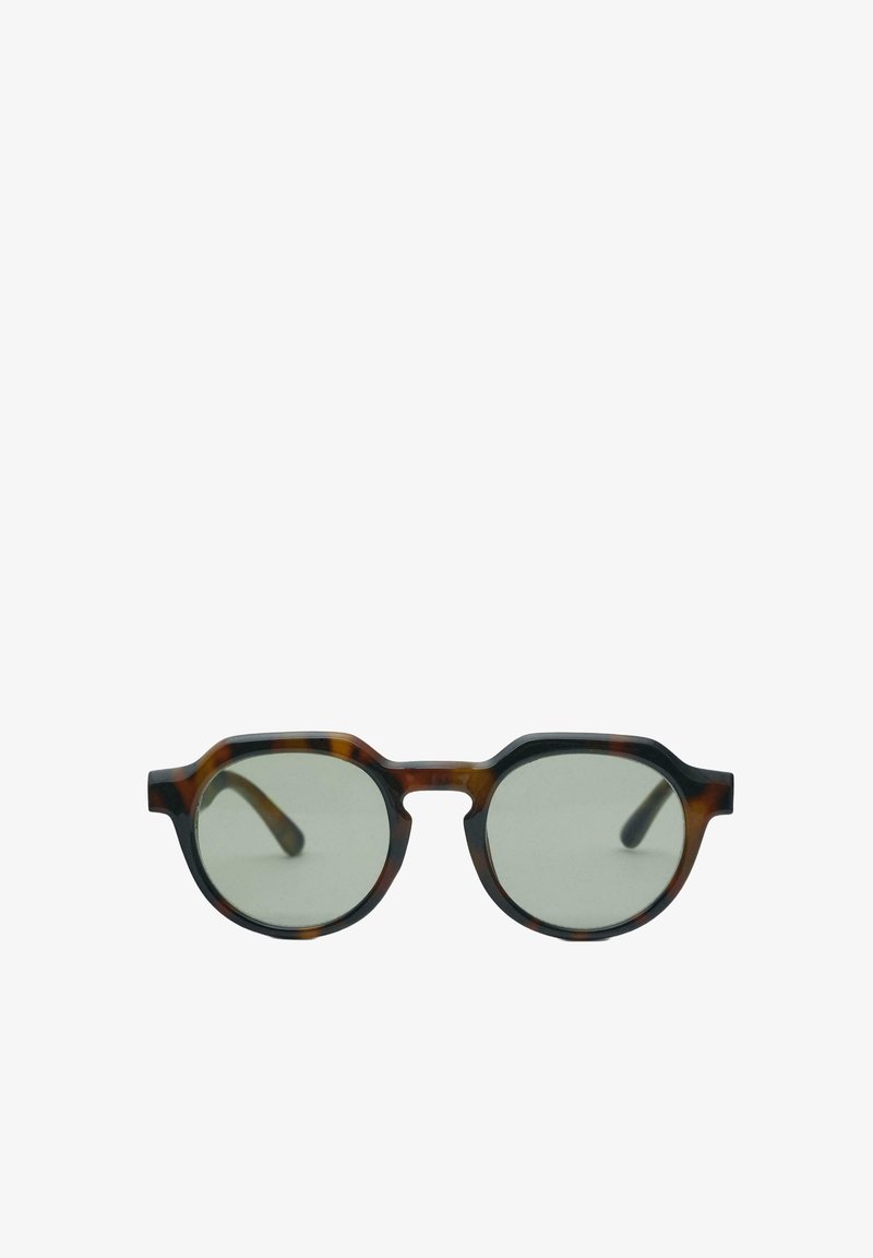 Lunettes rondes en écaille de tortue avec un pont en forme de serrure et des verres légèrement teintés sur fond blanc.