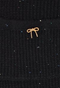 Schwarzer gestrickter Stoff mit einer gerippten Textur, verziert mit verstreuten kleinen, mehrfarbigen Pailletten und einem goldenen metallischen Schleifenakzent.