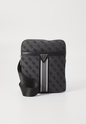 Compact gray and black Guess crossbody bag with monogram pattern, vertical stripe, and adjustable black shoulder strap on white background.