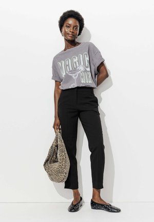 T-shirt graphique gris avec le texte "MAGIC MIX", pantalon noir ajusté, ballerines noires avec des clous, et un sac hobo à imprimé léopard.