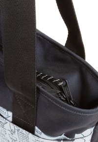 Mustansin kanka kantolaukku vetoketjullisella taskulla, jossa on valkoisia graafisia kuvioita. Vahvistetut hihnat ja teksturoitu pinta kestävyys. 