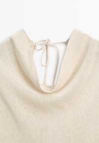 Beige strikket sweater med bred kighals og en tynd bindesnor i nakken.
