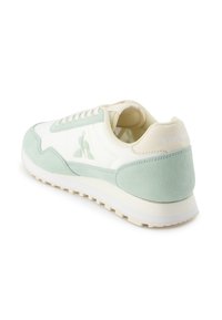 Zapato deportivo en verde claro y crema, hecho de ante y materiales sintéticos, con un logo blanco y suela de goma texturizada.