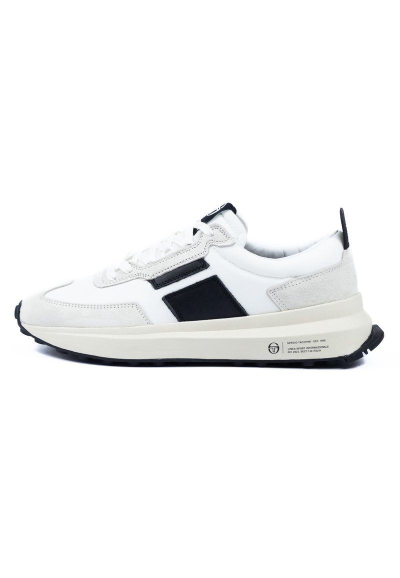 Weiße Sneakers mit schwarzen und grauen Wildleder-Akzenten, die eine abgerundete Zehenpartie, strukturierte Oberflächen und eine flache schwarze Gummisohle aufweisen.