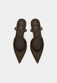 Mules à bout pointu en daim marron avec deux fines brides sur le dessus. Semelle intérieure texturée et logo doré visibles.