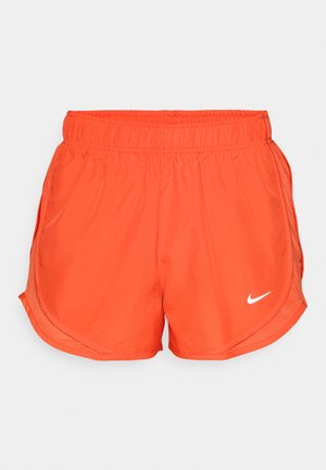 Oranžne športne kratke hlače z elastiko v pasu, stranskimi odprtinami in belim Nike logotipom na sprednji strani. Narejene iz gladkega, lahkega materiala.