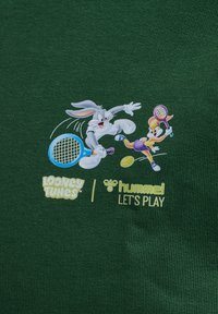 Tejido verde con un gráfico de Bugs Bunny y Lola Bunny jugando al tenis, con acentos coloridos y logotipos de Looney Tunes y Hummel.