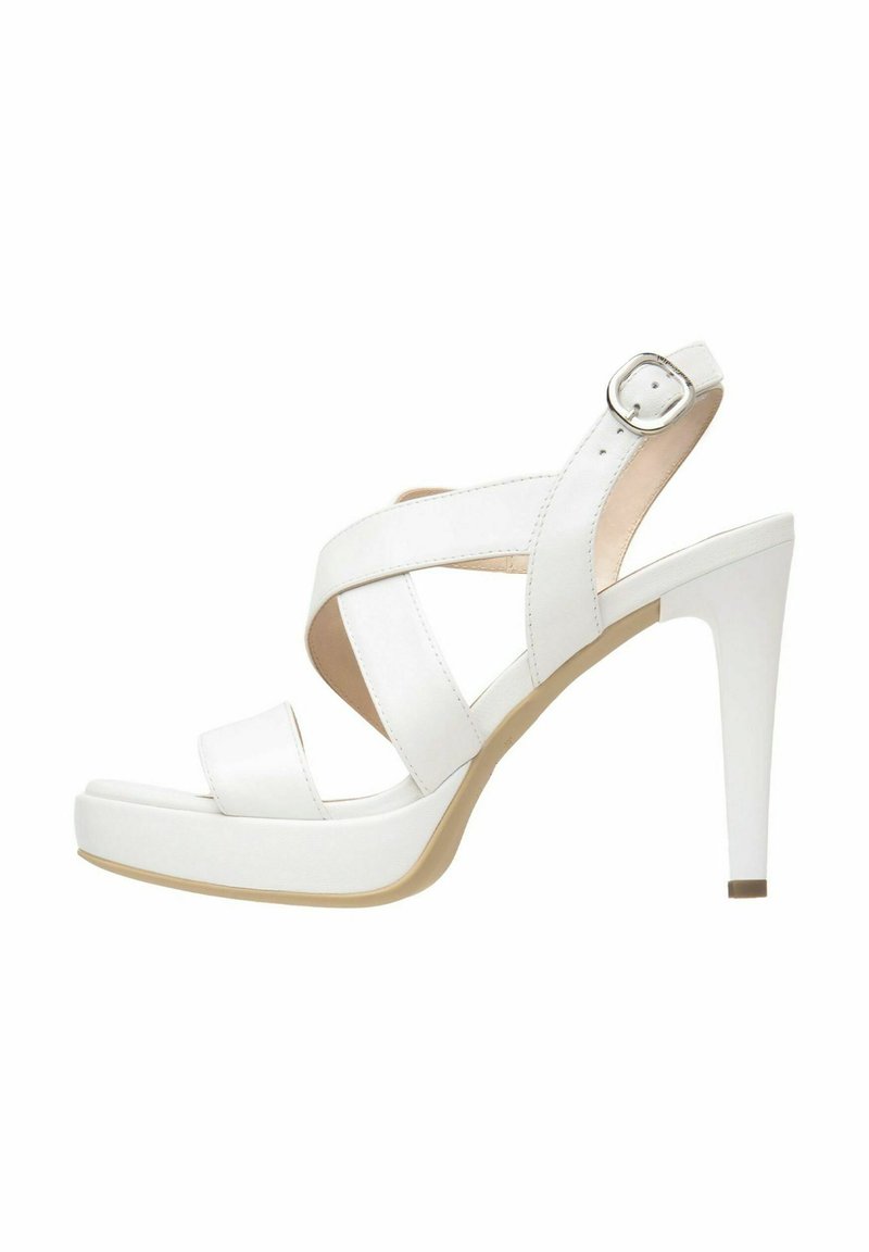 Sandale blanche à talons hauts avec un design à lanières croisées et une boucle ajustable à la cheville. Matériau synthétique lisse ; bout fermé avec une semelle à plateforme.