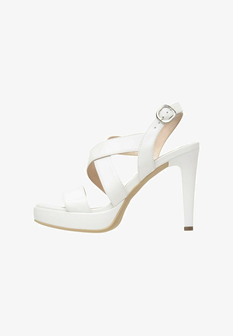 Sandale blanche à talons hauts avec un design à lanières croisées et une boucle ajustable à la cheville. Matériau synthétique lisse ; bout fermé avec une semelle à plateforme.