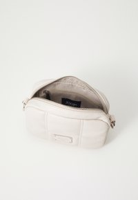 Borsa in pelle beige chiaro con chiusura a zip, forma rettangolare e dettagli cuciti. L'interno include un'etichetta del marchio e una tasca.
