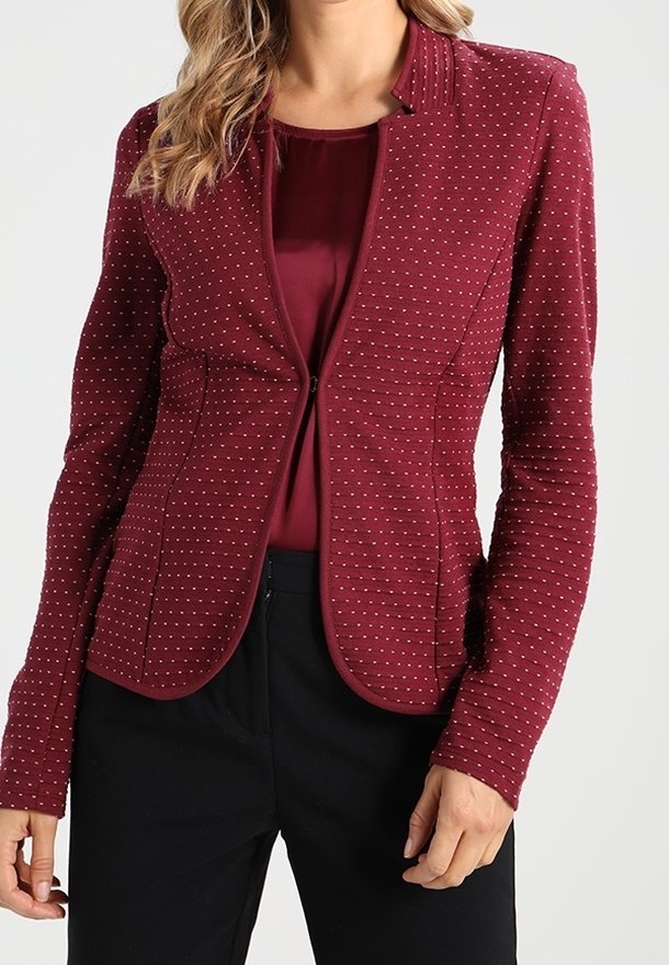 Bordowy żakiet dopasowany z teksturowanym wzorem, z okrągłym dekoltem, subtelnymi przeszyciami i długimi rękawami. Noszony na dopasowanej bluzce.
