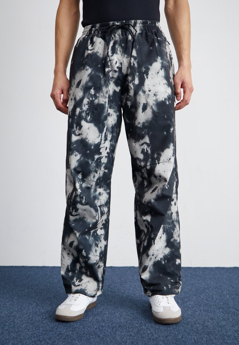 Svart og hvit tie-dye loungebukser med elastisk midjebånd og snøring. Løs passform med sidelommer, laget av et mykt stoff.