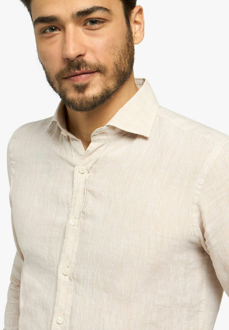 Camicia di lino beige con colletto, cinque bottoni e superficie texture. Presenta un design slim fit e una leggera lucentezza.
