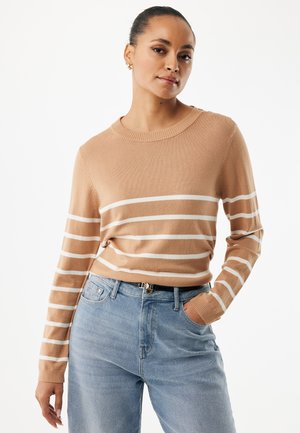 Tanfarvet stribet sweater med hvide, horisontale striber, rund halsudskæring og lange ærmer. Blød tekstur, kombineret med lyseblå denimjeans.