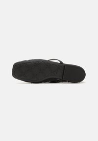 Black rubber sandal sole with a textured grip pattern, featuring raised dots for traction and a smooth back section.