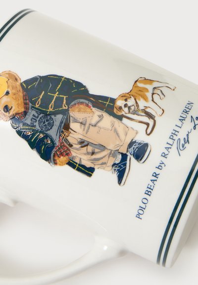 Ours habillé en vêtements décontractés, debout à côté d'un petit chien, avec le texte "POLO BEAR by RALPH LAUREN" sur une tasse en céramique blanche.