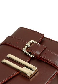 Borsa a tracolla in pelle marrone con una fibbia in metallo color oro e due barre accentuate parallele sulla parte anteriore, con dettagli cuciti lungo i bordi.