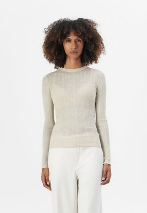 Lys beige langermet topp med fin ribbestruktur, rund hals, og tettsittende silhuett. Brukt med hvite vide bukser.