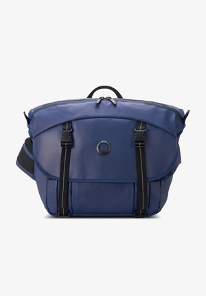 Zaino blu realizzato in tessuto resistente, presenta una forma arrotondata, chiusura con zip, spallacci regolabili e doppie fibbie frontali.