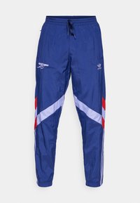 Modré sportovní kalhoty s lesklou texturou, s červenými a bílými diagonálními proužky, logem Adidas a emblémem Arsenalu. Elastický pás.