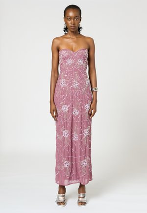 Abito maxi senza spalline di un rosa chiaro con ricami floreali e dettagli di perline. Indossato con tacchi a strappy argento, che mette in mostra una silhouette aderente.