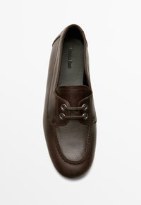 Brun læderloafer med afrundet tå, snøredetaljer og en tekstureret overflade; indvendigt prydet med præget mærkenavn.