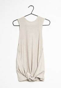 Haut sans manches beige clair en tissu texturé, avec un col rond et un détail noué en bas. Suspendu à un crochet noir.