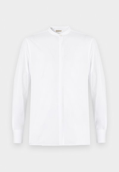 Λευκό πουκάμισο με μακριά μανίκια, γιακά μανταρίνι, καλυμμένο πάπλωμα κουμπιών και μανσέτες με κουμπιά, παρουσιασμένο σε απλό φόντο.