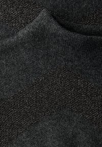 Ciemna dzianina o wzorze jodełki. Zawiera subtelne metaliczne nici, tworzące teksturę i wizualne zainteresowanie w różnych odcieniach szarości.