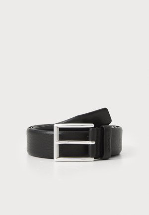 Ceinture en cuir noir avec une boucle rectangulaire à double ardillon en argent. Elle présente une texture lisse et un logo embossé sur la sangle de la boucle.