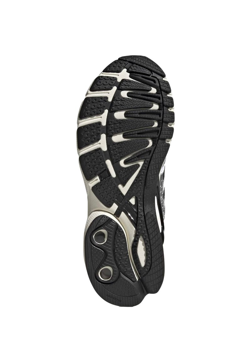 Semelle de chaussure de sport noire et blanche avec un motif de bande de roulement texturé et des éléments de coussin circulaires près du talon pour l'absorption des chocs.