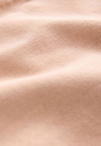 Jasnoróżowa tkanina o gładkiej, miękkiej fakturze i drobnym prążkowanym wzorze, prezentująca delikatne odcienie kolorów i matowe wykończenie.