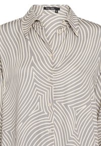 Button-up shirt in grey with white wavy pattern. Made from smooth fabric, featuring a collar and five buttons down the front.