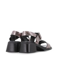 Sandalias de tacón abiertas con una suela texturizada negra, correas metálicas rosas con un patrón agrietado y una correa ajustable en el tobillo.