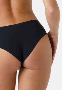 Slip bikini nera in tessuto elasticizzato con design a taglio alto, texture liscia e copertura minima, caratterizzata da ritagli laterali per un look elegante.