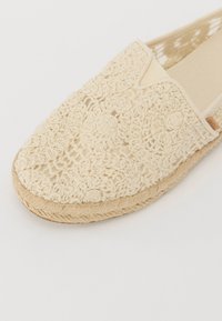 Pletené espadrilky v béžové barvě, s texturovaným květinovým vzorem, měkkým textilním svrškem a juty rope podrážkou. Uzavřená špička s designem na klouzání.