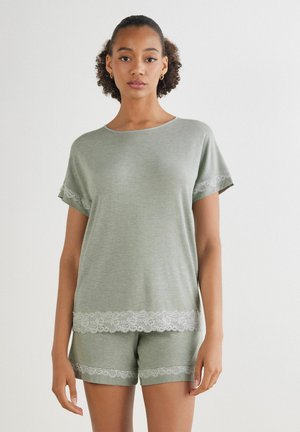 Ljusgrön kortärmad topp och shorts-set, tillverkat av mjukt material, med vita spetsdetaljer på ärmar och fåll för extra stil.