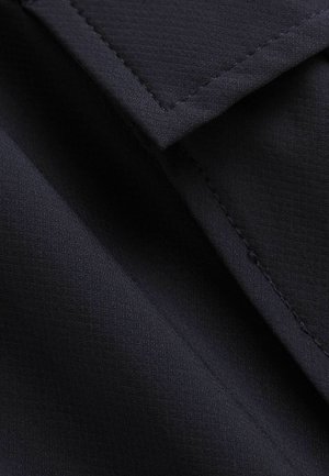 Marine stof met een subtiele rasterstructuur, met overlappende secties en schone, rechte stiksels langs de randen.