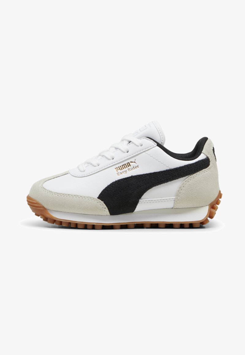 White sneaker with a black suede stripe, suede toe cap, and gum rubber sole. Features lace-up design and gold logo detailing on the side.