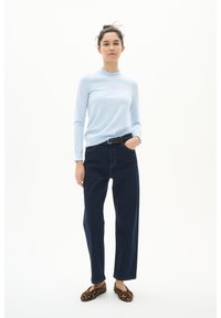 Light blue long-sleeve top with ruffled neckline, dark blue wide-leg jeans, and leopard print flats, posed against a white background.