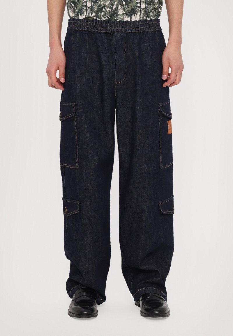 Pantaloni cargo bleu închis din material denim, cu un tiv elastic, mai multe buzunare laterale și detalii de cusătură contrastante.