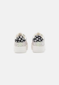 Baskets fleuries avec une tige textile à motif en noir et blanc, des accents vert menthe et une semelle en caoutchouc blanche. Vue arrière montrant un design à double motif.
