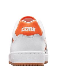 Sneaker bianco con tacco arancione e branding "CONS". Presenta una superficie testurizzata e suola in gomma per una buona aderenza.
