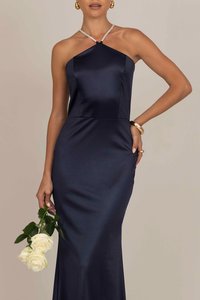 Navy satin mekko, jossa on kiinnitys kauluksella ja istuva leikkaus, sekä halkio. Mekon kaula-aukkoa korostaa kristallit, ja siihen on lisätty valkoisia ruusuja.