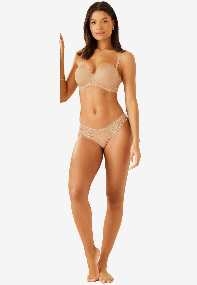 Beige melltartó szett, díszes csipkás szélekkel, párnázott melltartóval és hozzáillő tanga alsóval, sima textúrával és diszkrét takarással.