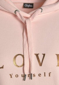 Pink hoodie med en blød tekstur, med et guld folie-tryk der siger "LOVE Yourself." Inkluderer snore med metalspidser.
