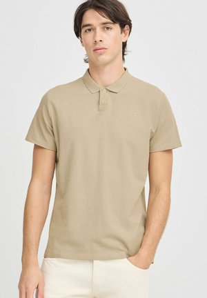 Beige színű pamut póló, gallérral és rövid ujjakkal. Diszkrét logóval az emlőrészen és laza szabással rendelkezik.