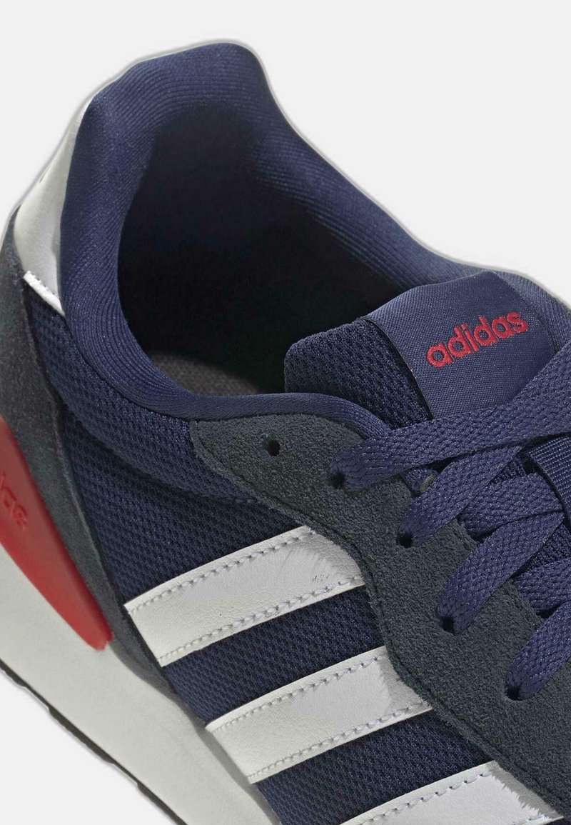 Marineblaue Sportschuh mit Mesh-Obermaterial, drei weißen Streifen, roten Akzenten und rutschfester Gummisohle. Verfügt über Wildlederdetails in der Nähe der Ferse.