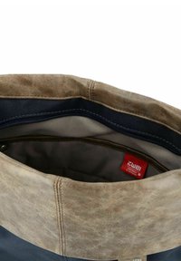Borsa in pelle marrone con un interno in tessuto blu navy. Presenta una parte superiore pieghevole, chiusura con zip e un'etichetta del marchio rossa all'interno. Texture liscia.