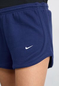 Navy blue ribbed athletic shorts featuring a white Nike logo on the lower left side and a wide, elastic waistband for comfort.